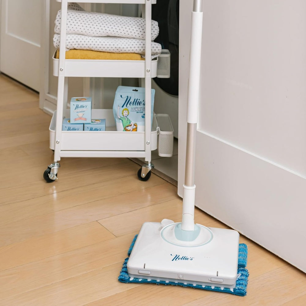 Nellie's Wow Mop on hardwood floor with blue microfiber pad in action near a white storage cart.