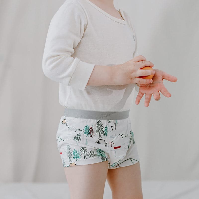 Nest Designs Bamboo Boys Boxer Briefs Forest Fun; toddler in white shirt shows tree-print briefs with a soft grey waistband.
