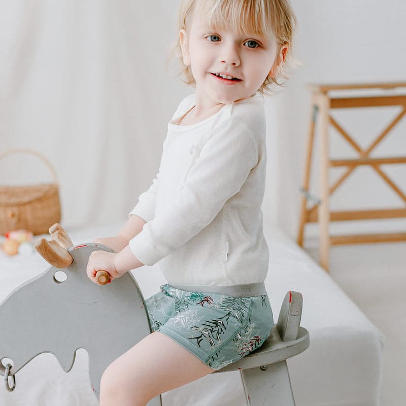 Nest Design Bamboo Boys Boxer Briefs Underwear (2 Pack) Forest Fun; toddler sits on a wooden rocker wearing forest-print briefs.