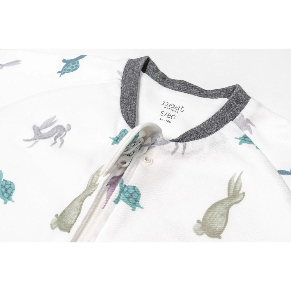 Nest Designs Avocado Bamboo Long Sleeve Footed Sleep Bag 1.0 Tog in white with gray trim, tortoise-hare print; zipper open.