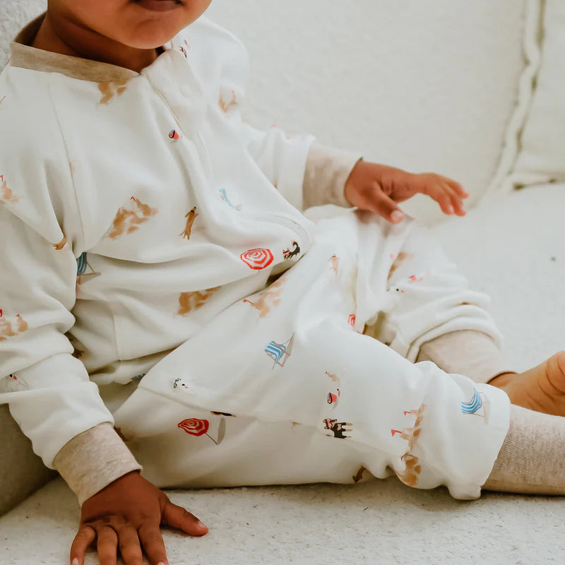 Nest Designs Avocado Bamboo Long Sleeve Footed Sleep Bag Beach Daze 1.0 Tog in white, baby lounging in sleepwear.