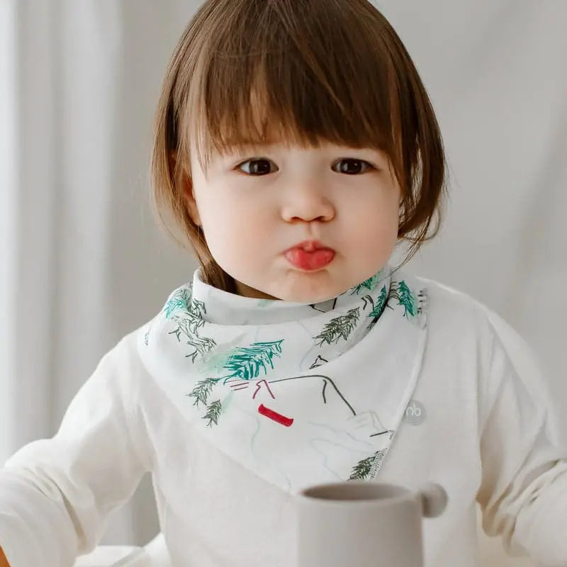 Nest Designs Bamboo Baby Bandana Bib One Size worn by a toddler at mealtime, white with green bamboo print.