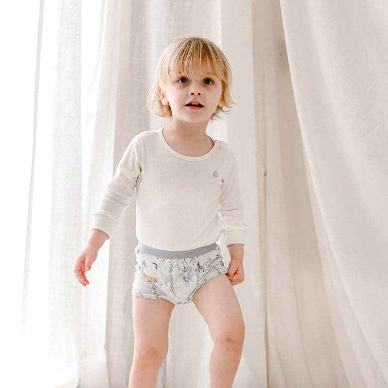 Nest Designs Bamboo Boys Boxer Briefs Underwear (2 Pack) Deep Blue Wonders; toddler stands in white shirt wearing soft, printed briefs.