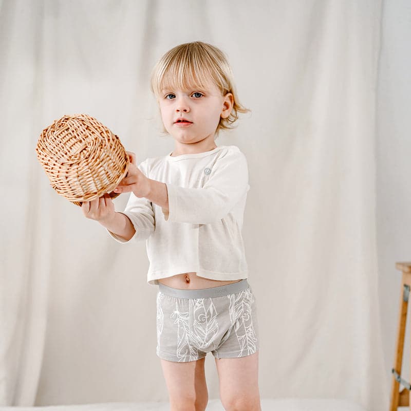 Nest Designs Bamboo Boys Boxer Briefs (2 Pack) Feather Light; toddler stands in grey leaf-pattern briefs, reaching with a wicker ball