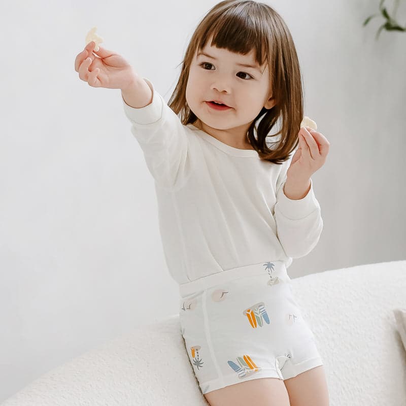 Nest Designs Bamboo Girls Boy Short Underwear Surf Camp 2-pack, worn by a girl in a white top with surf-print shorts.