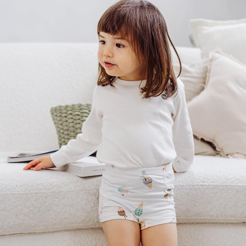 Nest Designs Bamboo Girls Underwear (2 Pack) Sweet Treats: a girl wearing white briefs with pastel ice cream prints at home.