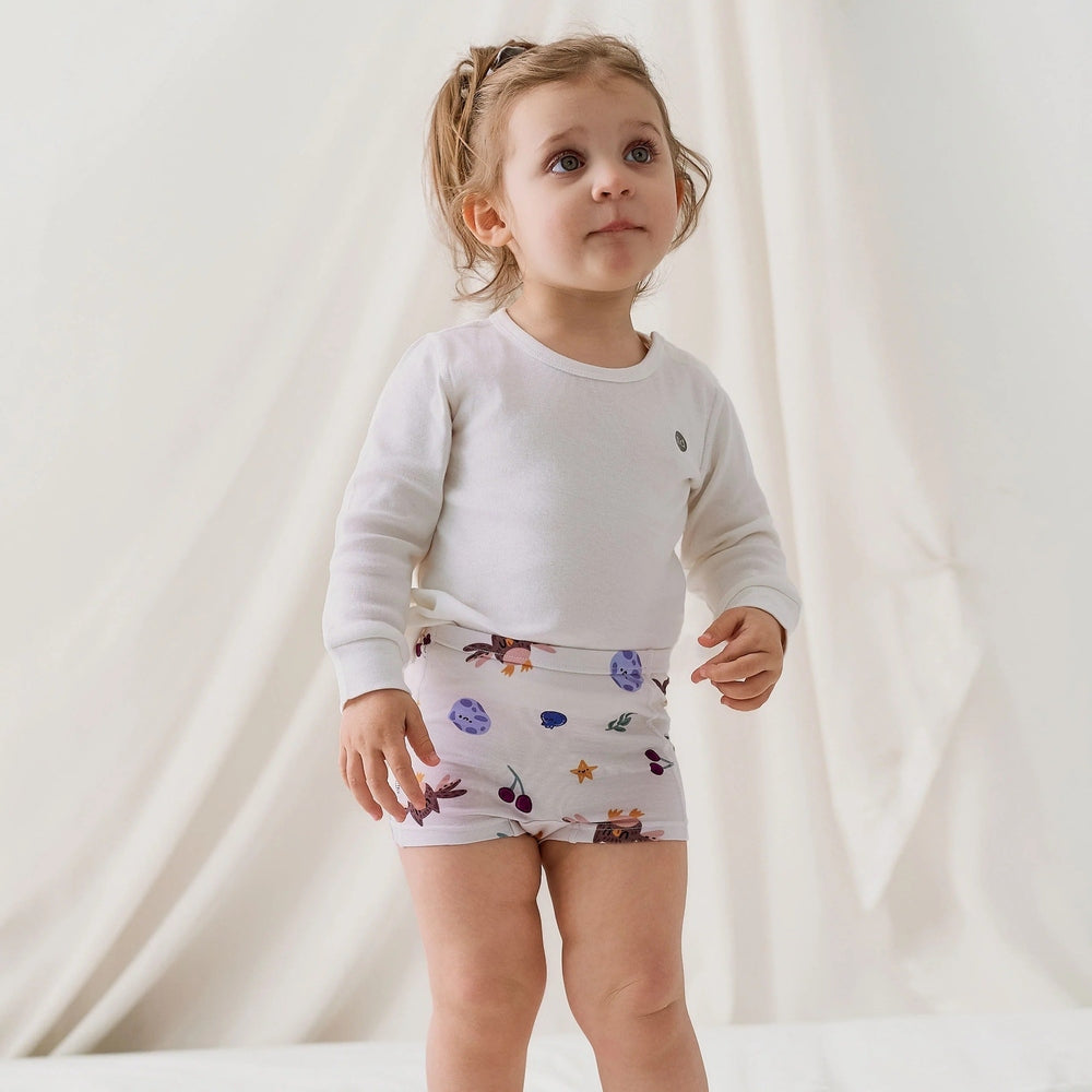 Nest Designs bamboo jersey girls boy shorts 2-pack, white with a colorful fall print, on a toddler.