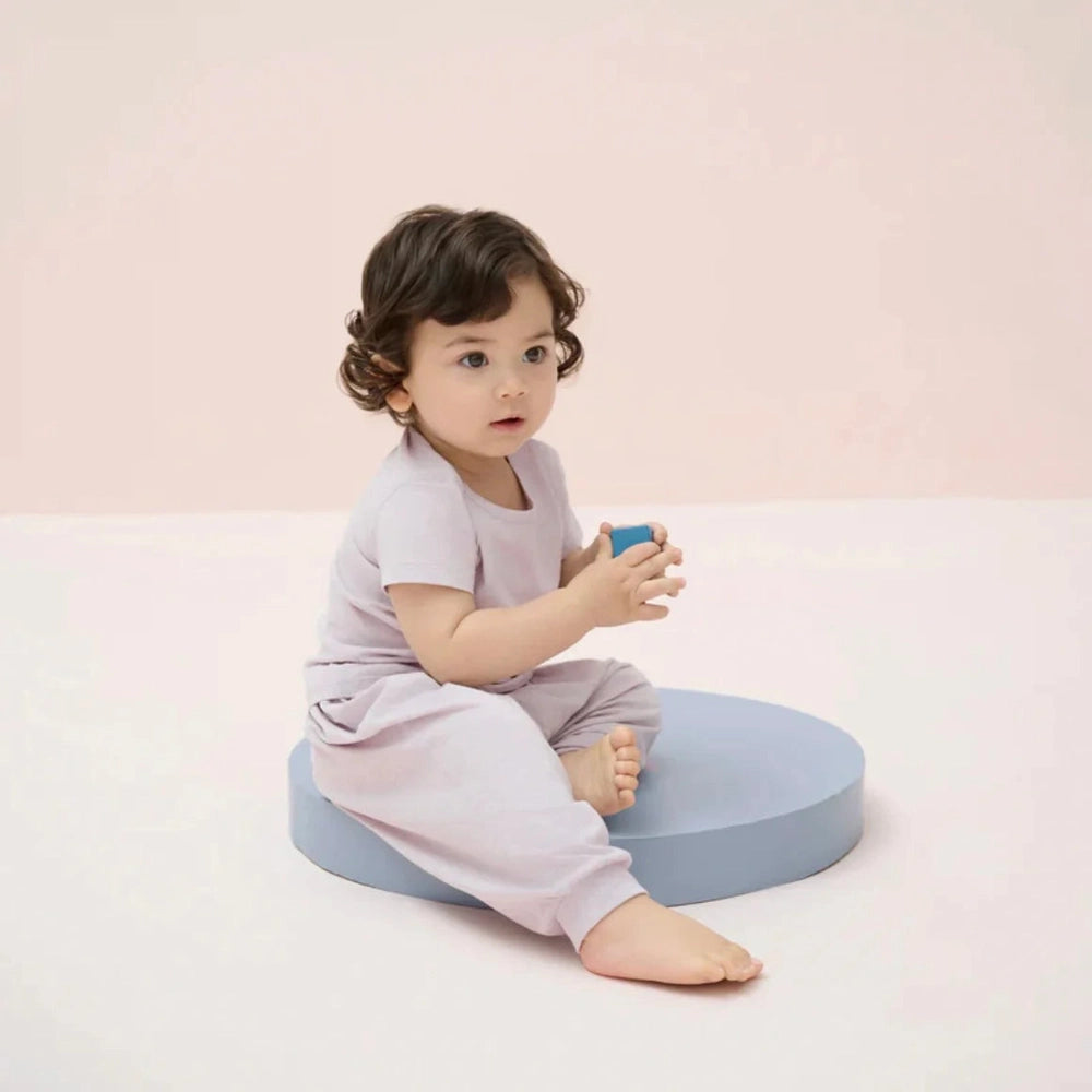 Nest Designs Bamboo Jersey Harem Pants Lavender Blue; baby sits on a blue round cushion, holding a blue block.