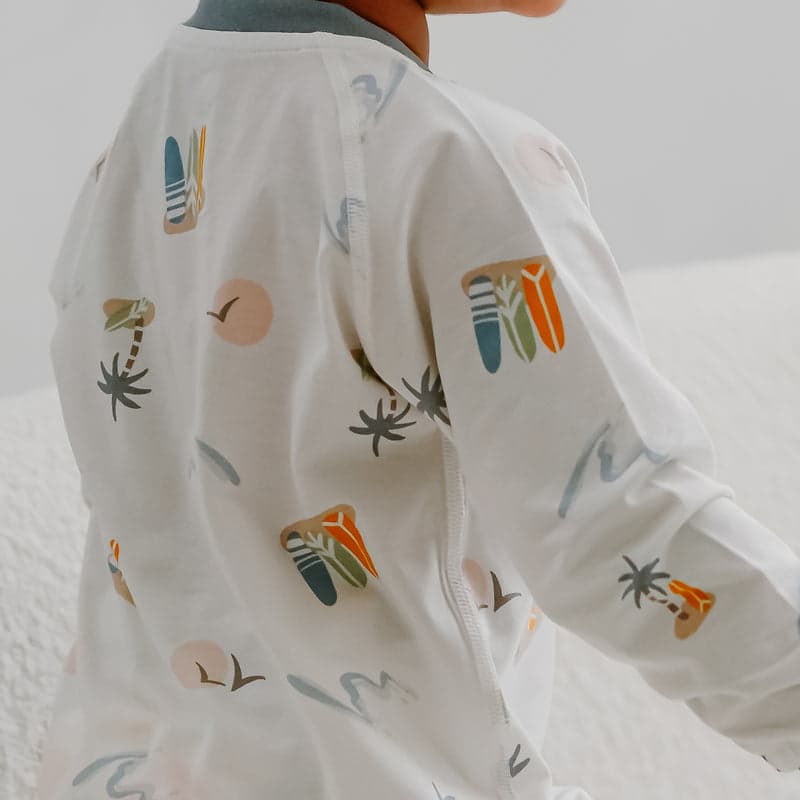 Nest Designs bamboo jersey zip-footless sleeper in pastel waves, baby standing and turning to reveal the back zipper