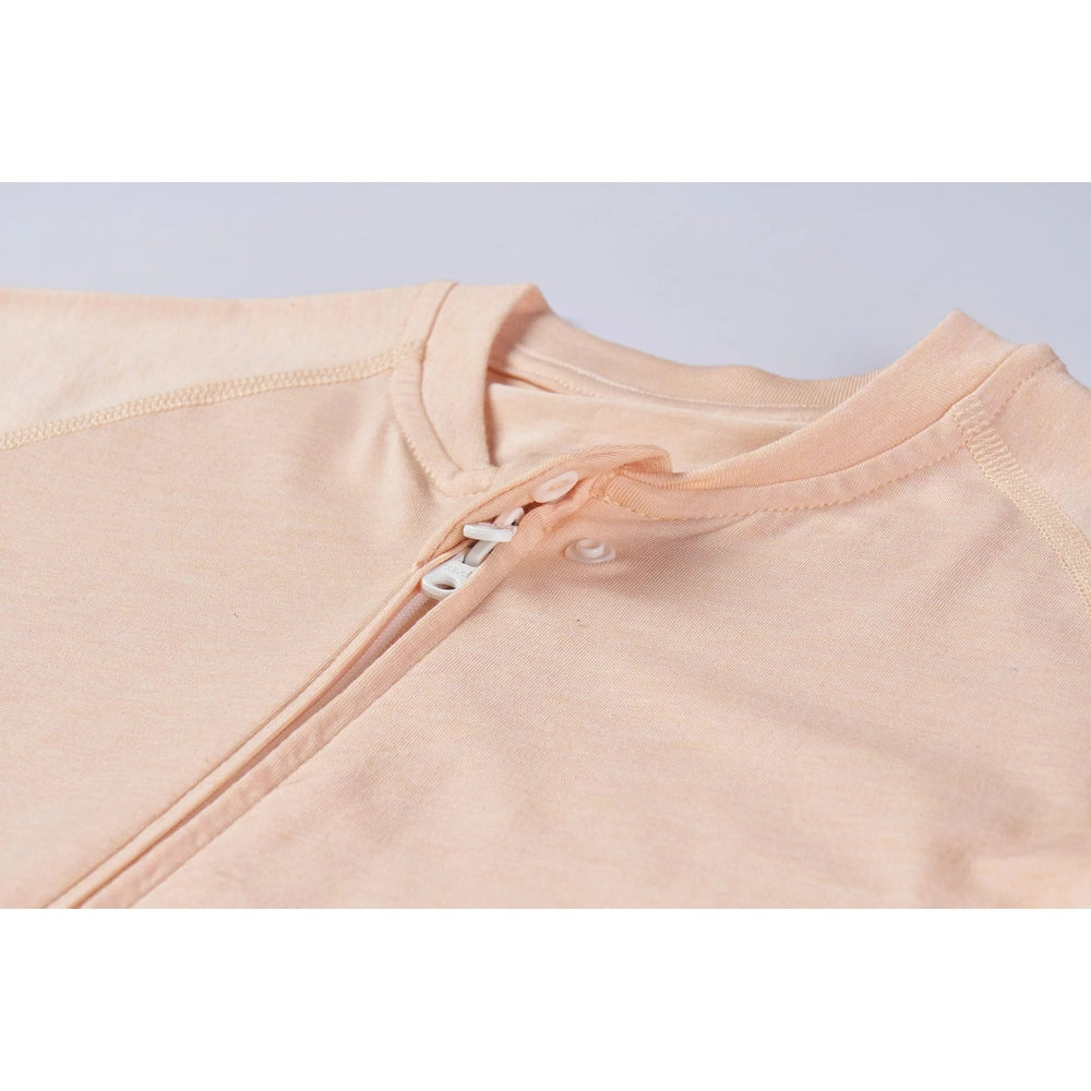 Nest Designs bamboo jersey short-sleeve footed sleep bag in Pantone Bellini peach, zipper closure shown.