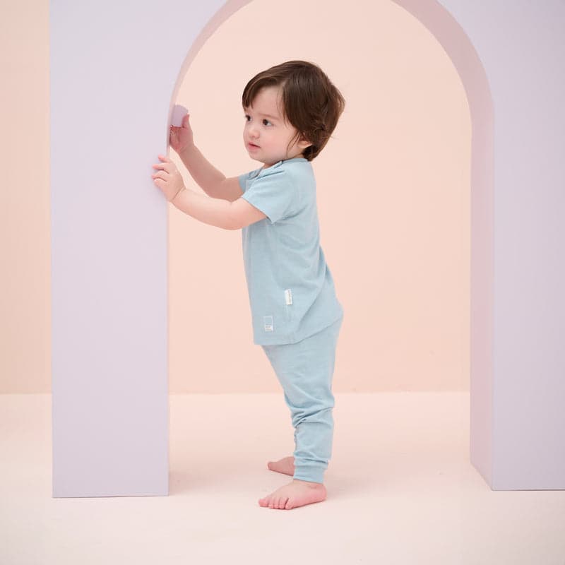 Nest Designs Forget-Me-Not bamboo jersey short-sleeve toddler PJ set; toddler stands barefoot, touching pastel arch.