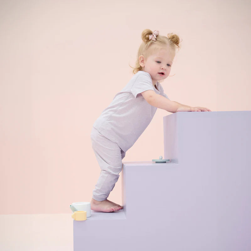 Nest Designs Bamboo Jersey Short Sleeve PJ Set Lavender Blue; toddler climbs pastel steps in soft lavender-blue PJs.
