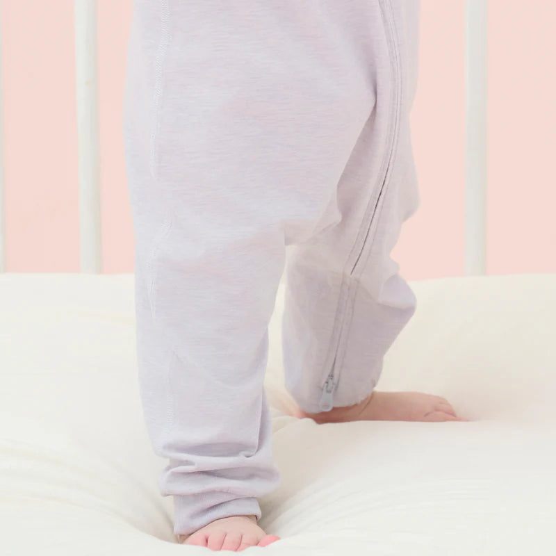 Nest Designs Bamboo Jersey Short Sleeve Slant Opening Romper Lavender Blue; baby stands on a bed, showing the side zipper.