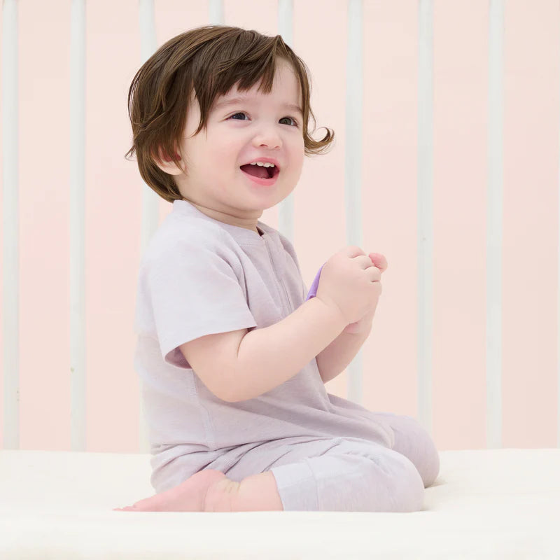Nest Designs Bamboo Jersey Short Sleeve Slant Opening Romper Lavender Blue on a smiling baby, sitting happily.