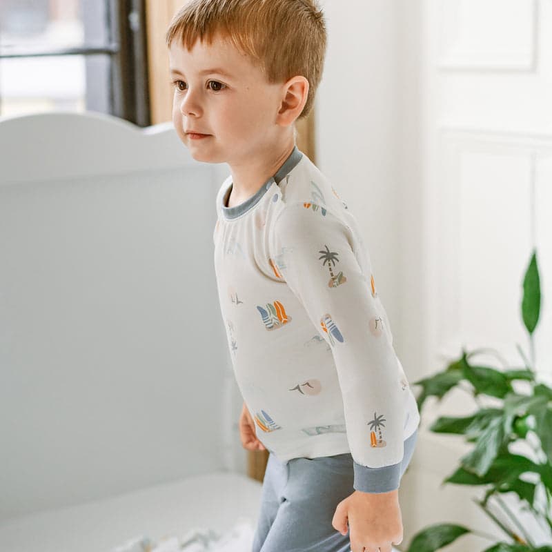 Nest Designs Bamboo Jersey Two-Piece Long Sleeve PJ Set Pastel Waves; toddler stands in light patterned sleepwear indoors.