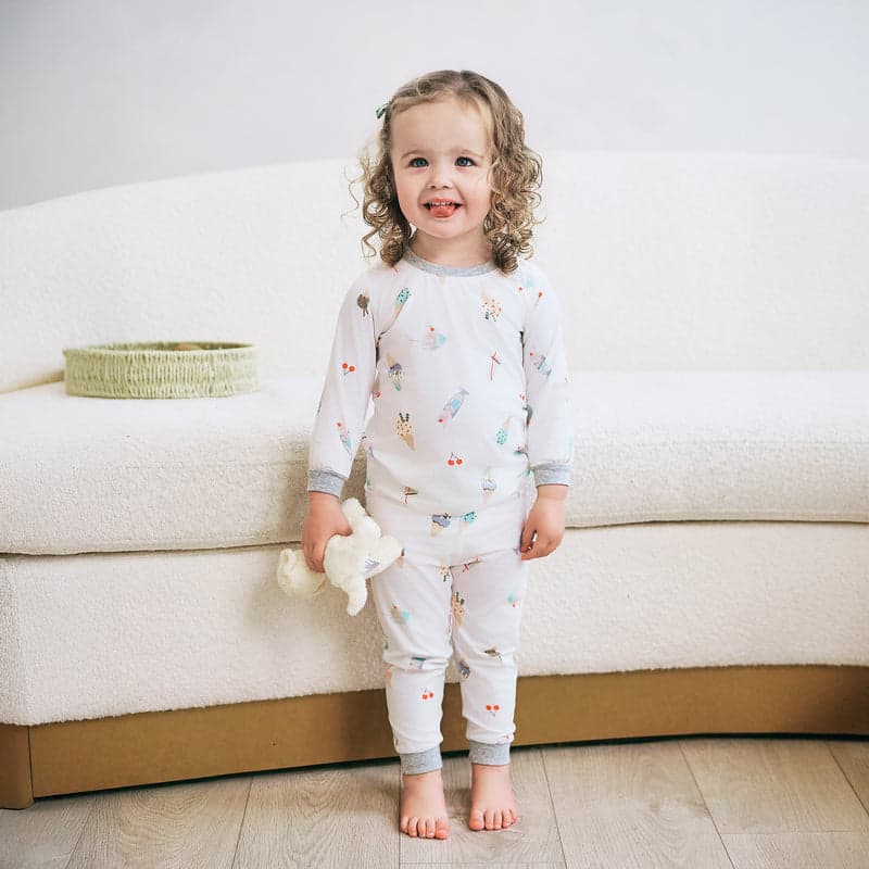 Nest Designs Bamboo Jersey Two-Piece Long Sleeve PJ Set Ice Cream Summer, white with ice cream print, worn by smiling toddler.