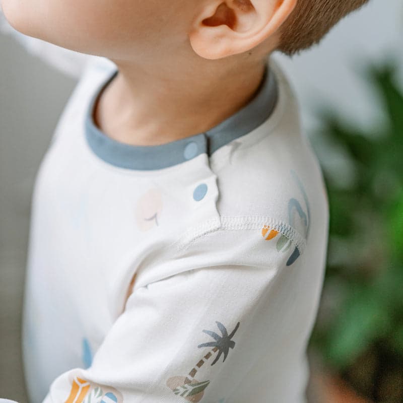 Nest Designs Bamboo Jersey Two-Piece Long-Sleeve Pajama Set in pastel waves, toddler wearing cream top with blue collar.