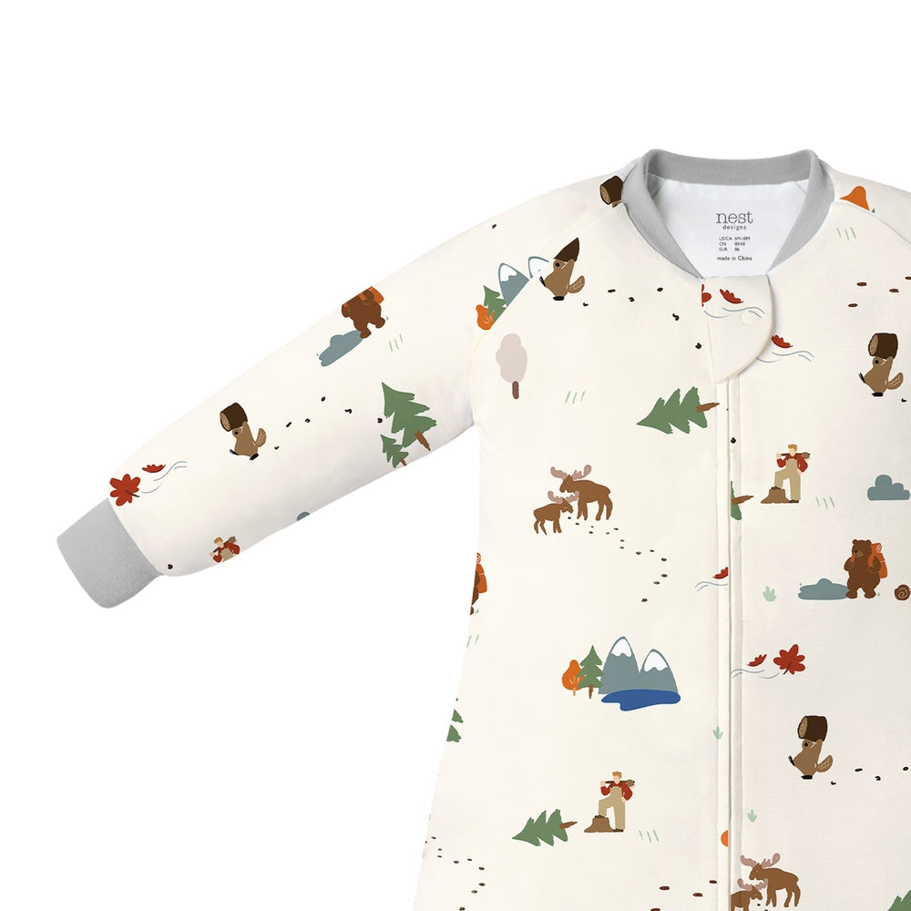Nest Designs Bamboo Long Sleeve Footed Sleep Bag 1.0 Tog Timber in cream with woodland prints, shown on a baby