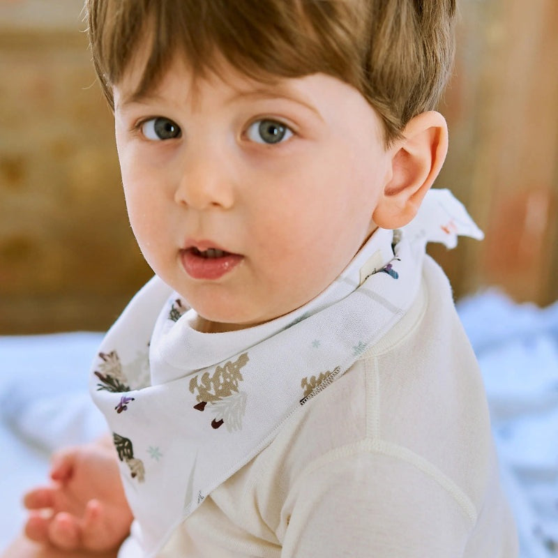 Nest Designs Bamboo Muslin Baby Bandana Bib Chills N' Thrills, soft white bib tied at back on a curious toddler.