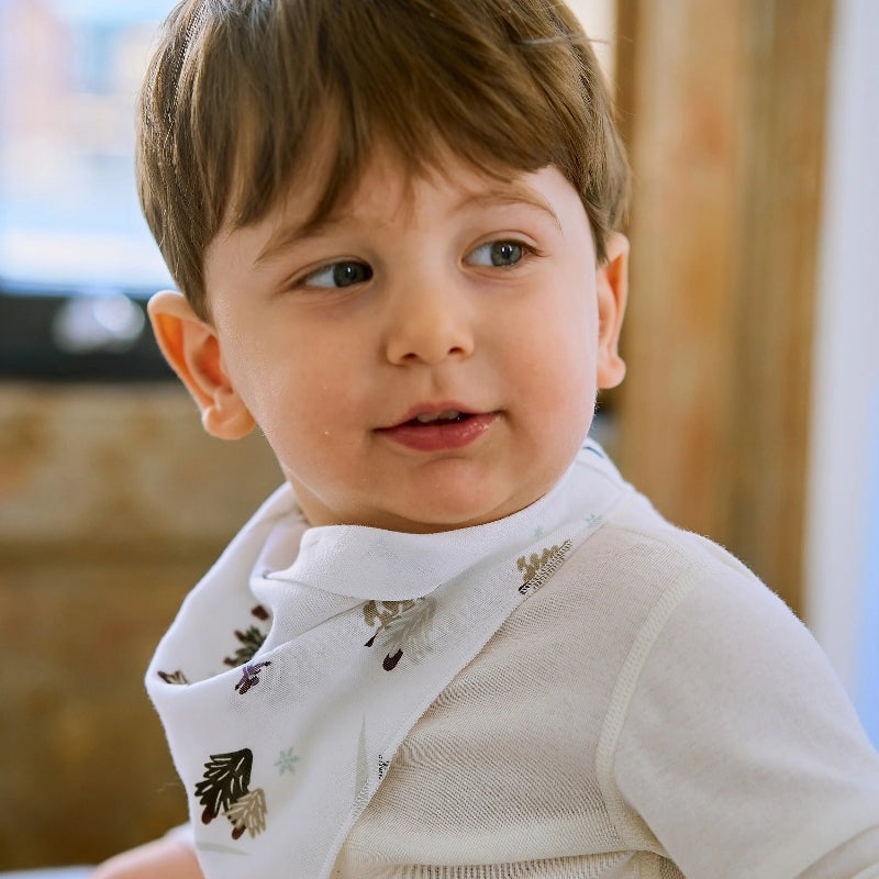 Nest Designs Bamboo Muslin Baby Bandana Bib Chills N' Thrills, white bib worn by a smiling toddler.