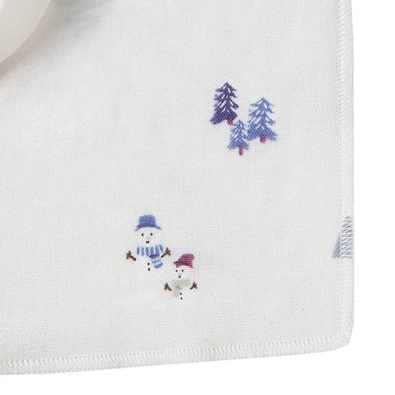 Nest Designs Bamboo Muslin Baby Bandana Bib Frosty Fun white bib with snowmen and pine trees, visible stitched edge.