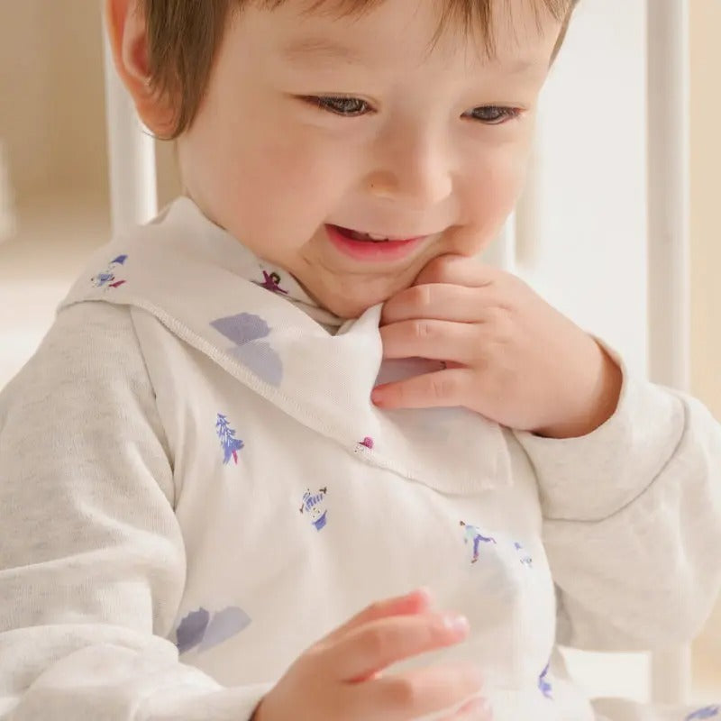 Nest Designs Bamboo Muslin Baby Bandana Bib Frosty Fun on a smiling toddler as he grips the bib.