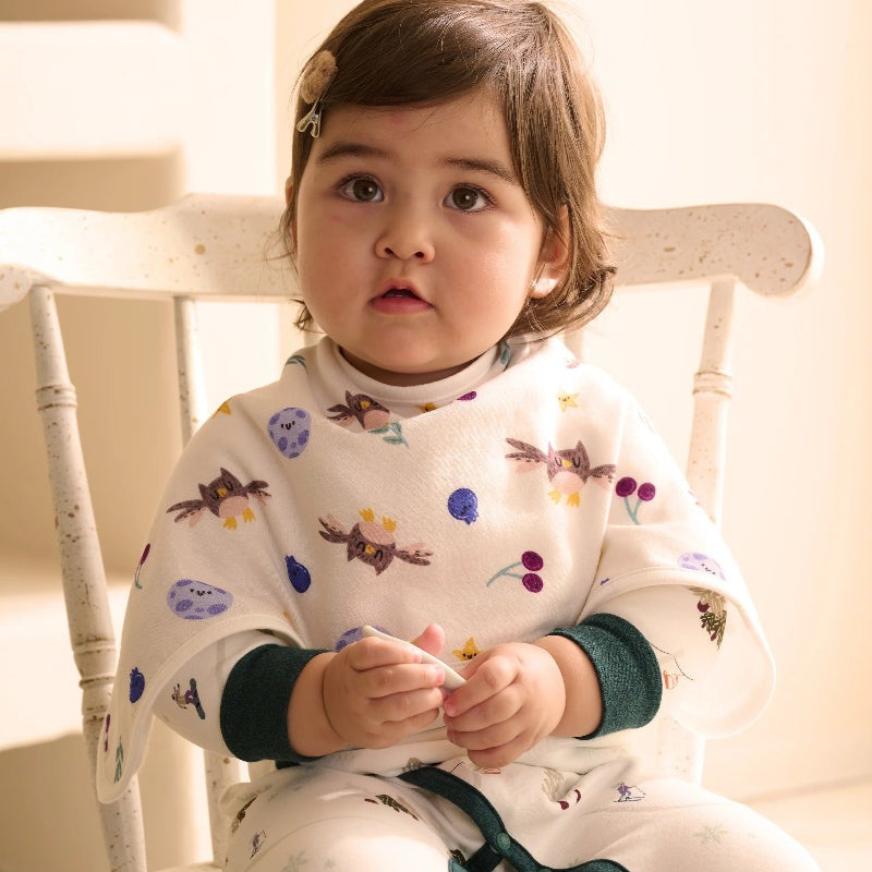 Nest Designs Bamboo Muslin Burp n Bib 2 Pack Fall Magic; white bibs with colorful owl and berry prints on a baby.