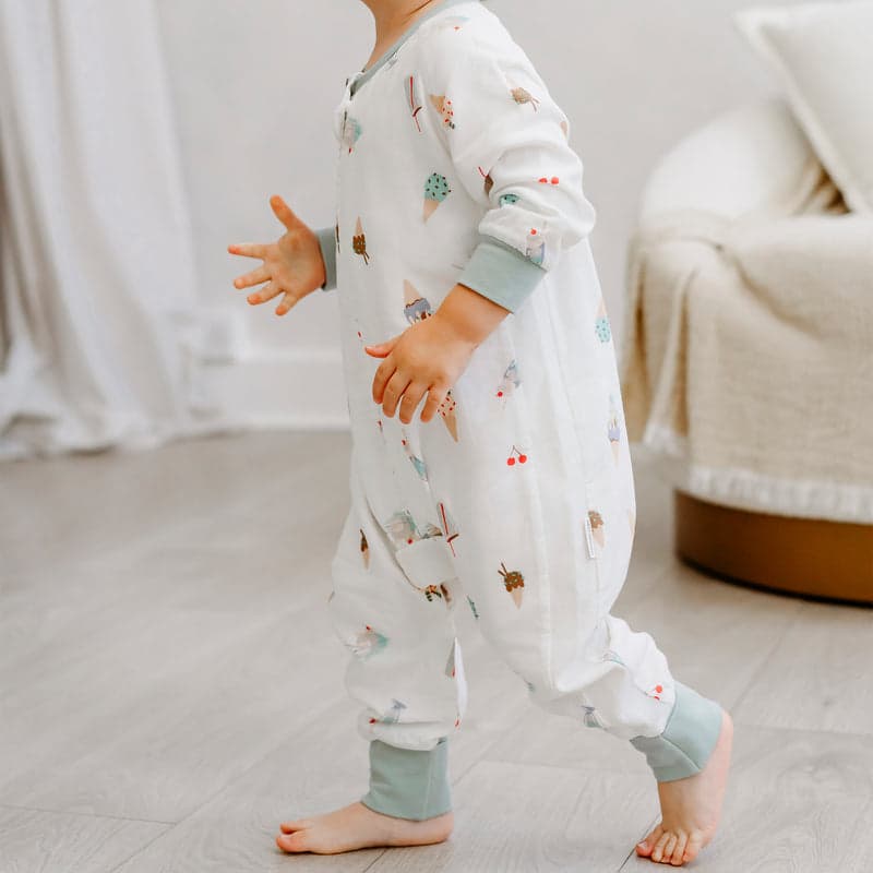 Nest Designs Bamboo Pima long-sleeve footed sleep bag Ice Cream Summer; white with pastel prints, toddler walking indoors.