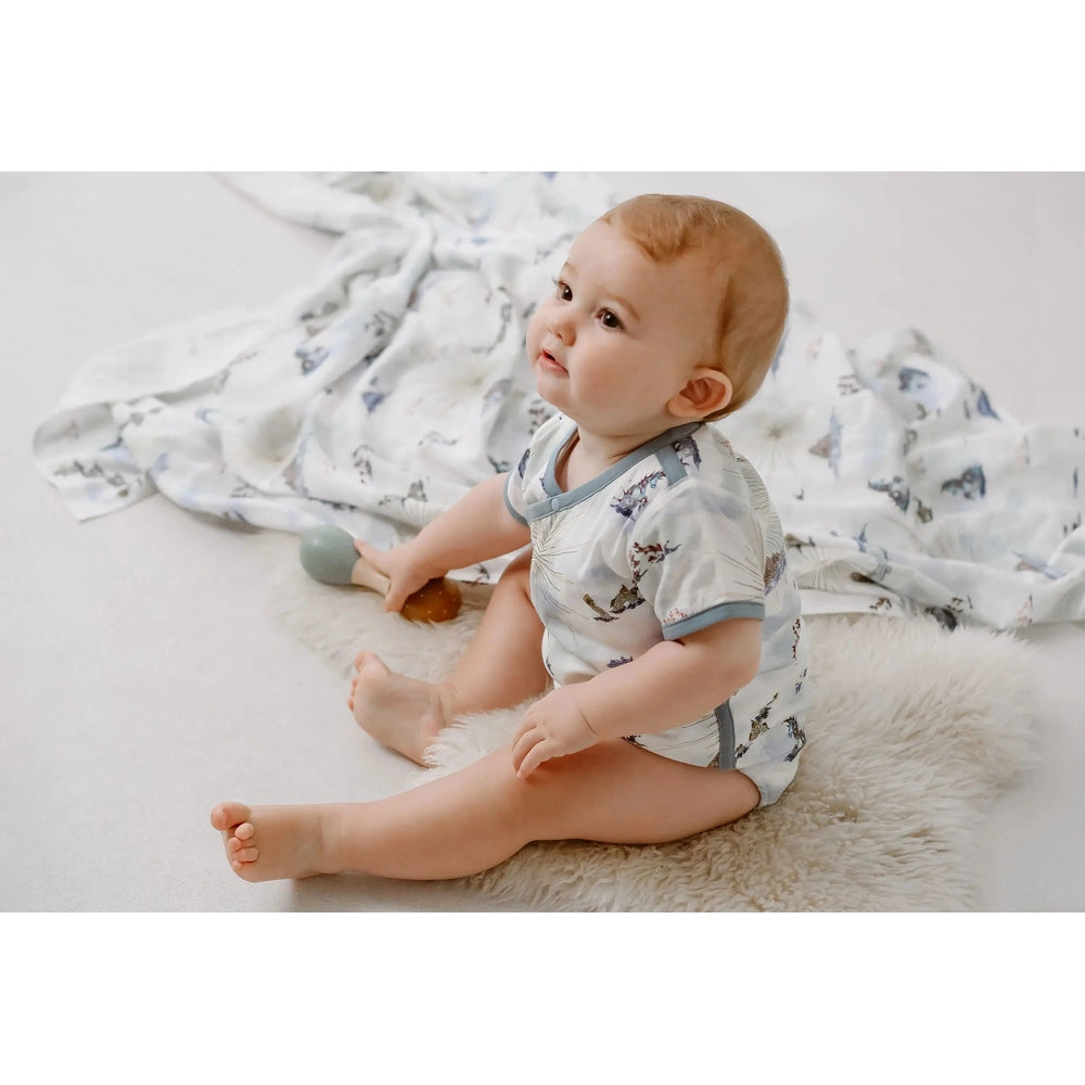 Nest Designs Bamboo Short Sleeve Kimono Onesie Ocean Wonders, baby sitting on fluffy rug in pale blue ocean print.