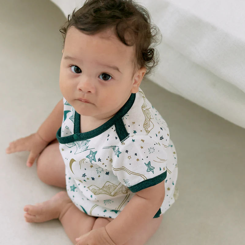 Nest Designs Bamboo Short Sleeve Kimono Onesie Stars White worn by a baby sitting up, showcasing green trim and star pattern.