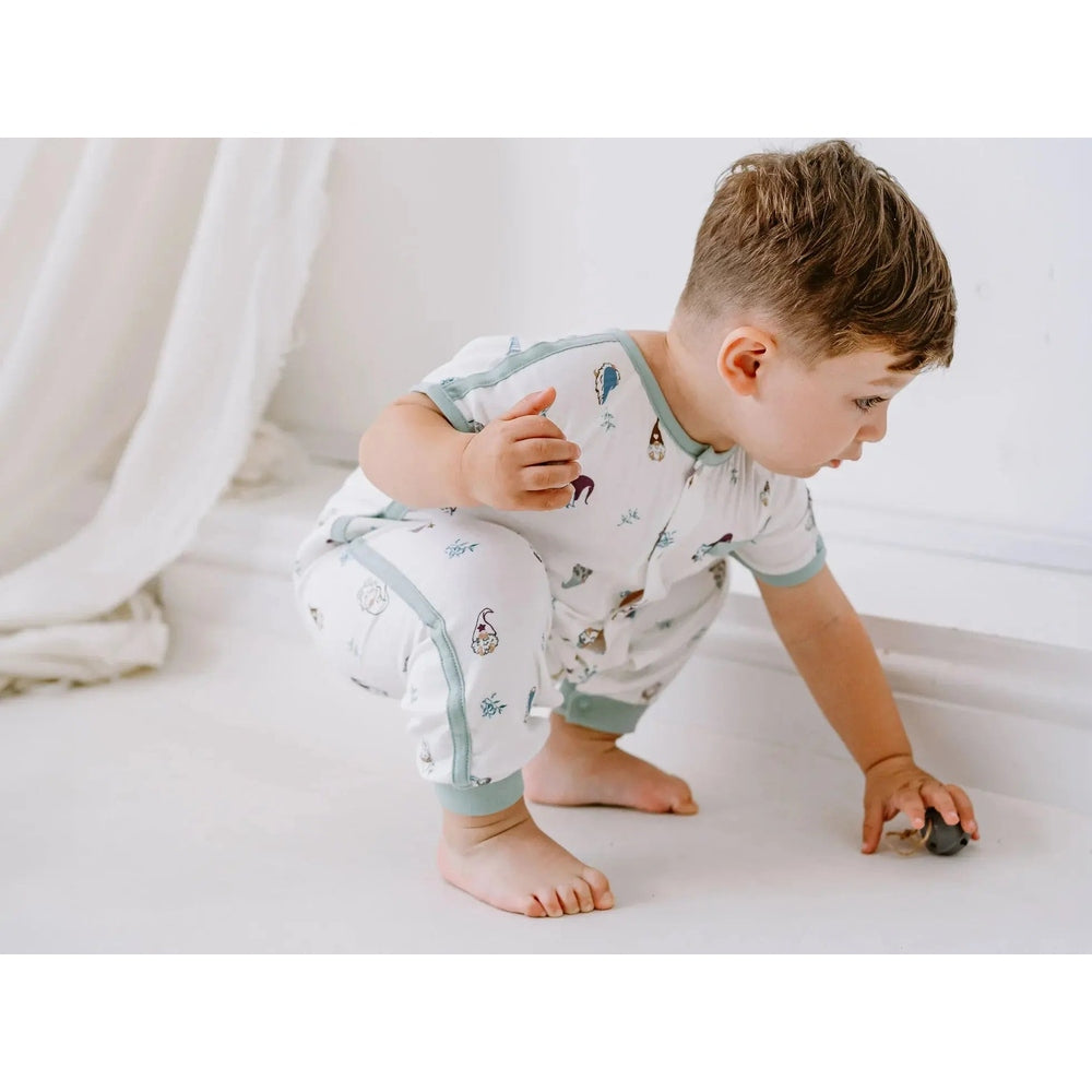 Nest Designs Bamboo Short Sleeve Romper Oh Gnome, white with pastel gnomes; toddler crouches to grab a toy.