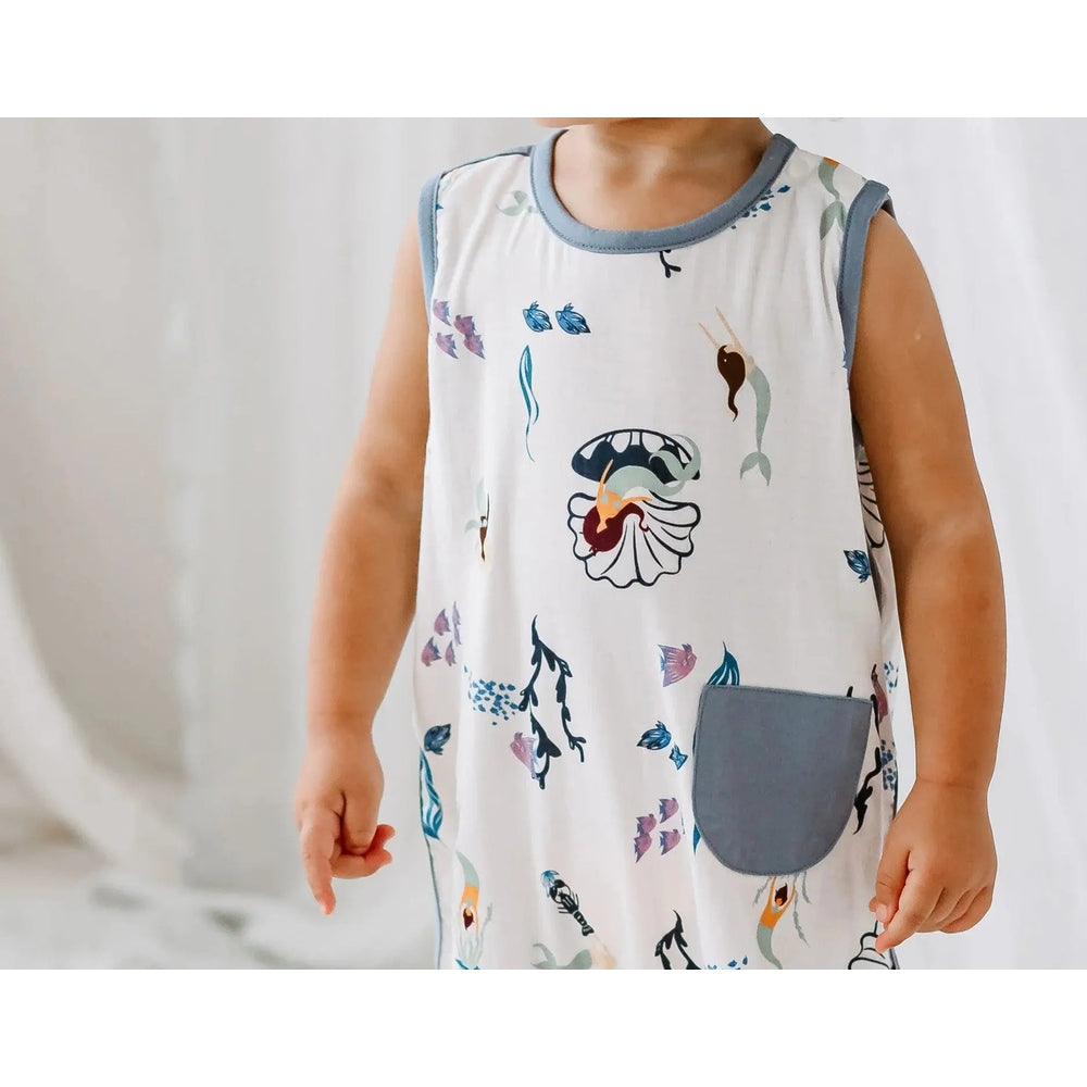 Nest Designs Bamboo Sleeveless Romper Splish Splash, toddler wears it upright, white with blue trim, sea-life print and blue pocket.