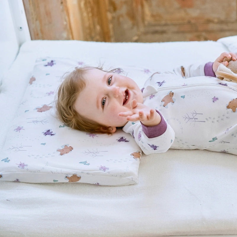 Nest Designs Bamboo Toddler Pillow with Snow Angels pillowcase, a smiling baby resting on the printed pillow.