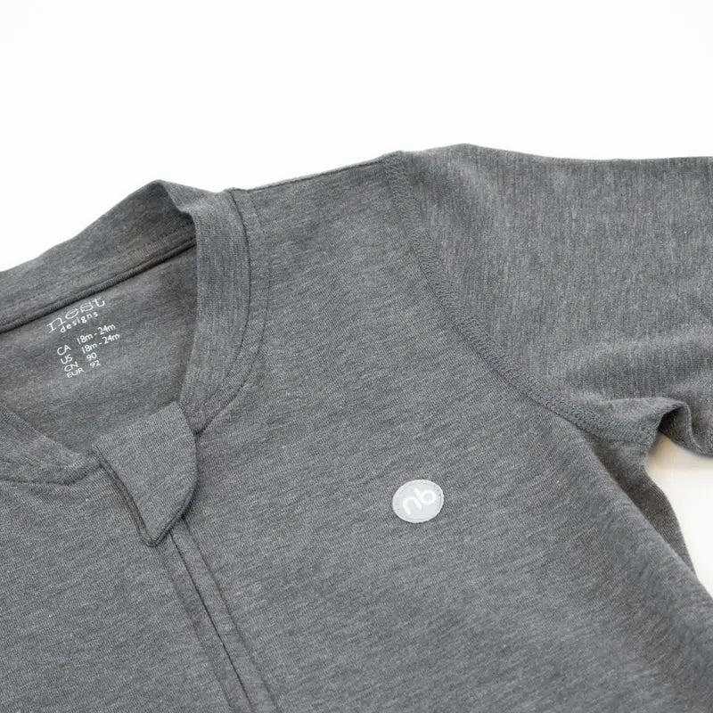 Nest Designs Basics Bamboo Cotton Short Sleeve Drop Bottom Romper Charcoal, shown laid flat with small logo badge.