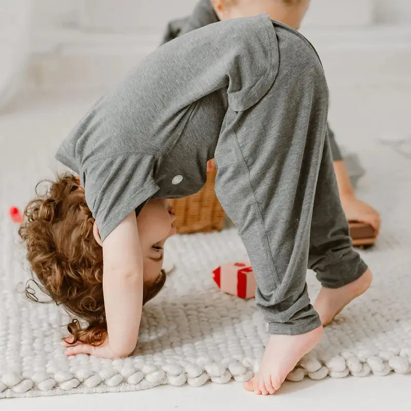 Nest Designs Basics bamboo cotton short sleeve drop bottom romper in charcoal; baby upside-down on a plush rug, crawling.