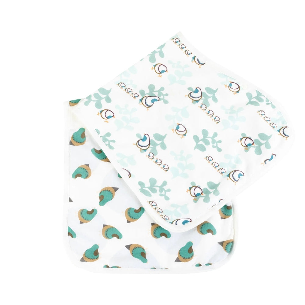 Nest Designs Burp'N Bib 2-pack: white bibs with teal birds and pastel leaves, one folded to show curved shape.