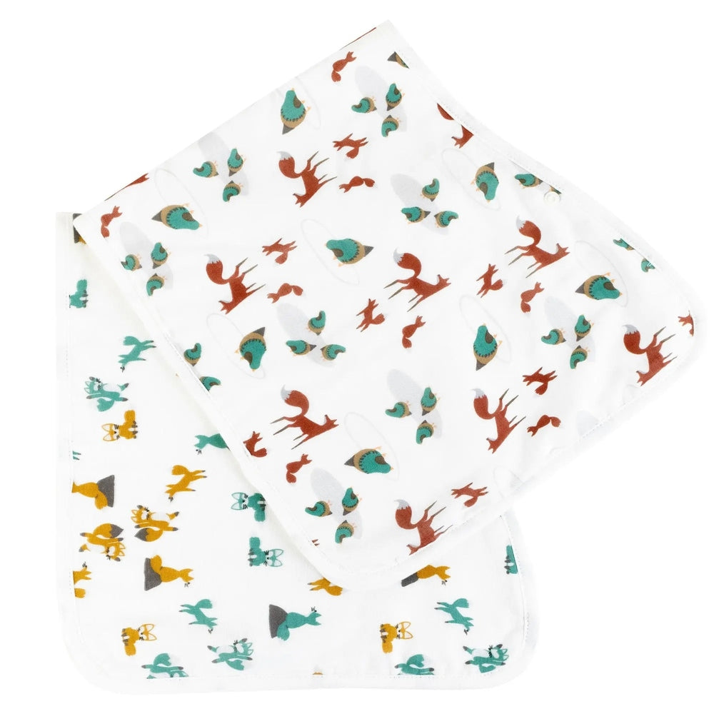 Nest Designs Burp'N Bib two-pack white bibs with teal, red and yellow dinosaurs laid flat.