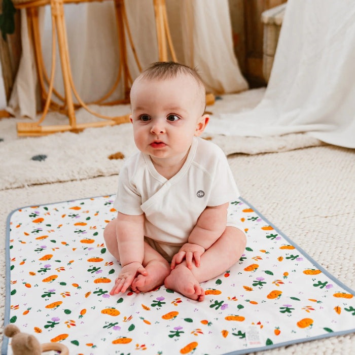 Nest Designs cotton waterproof baby change pad, Harvest Time print, baby sitting on mat