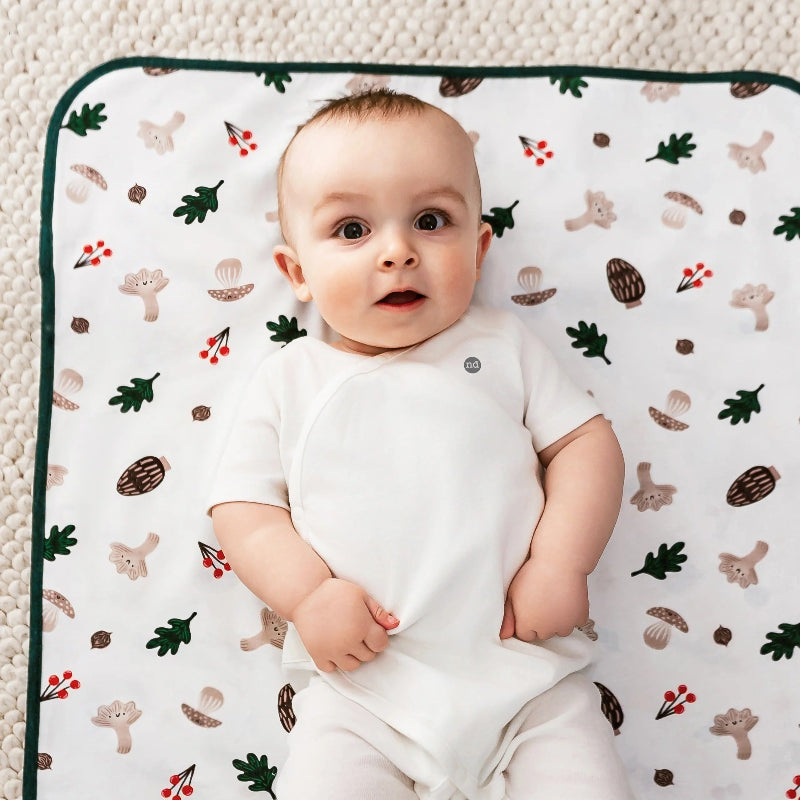 Nest Designs cotton waterproof baby change pad small with forest pattern on white, baby lying on it