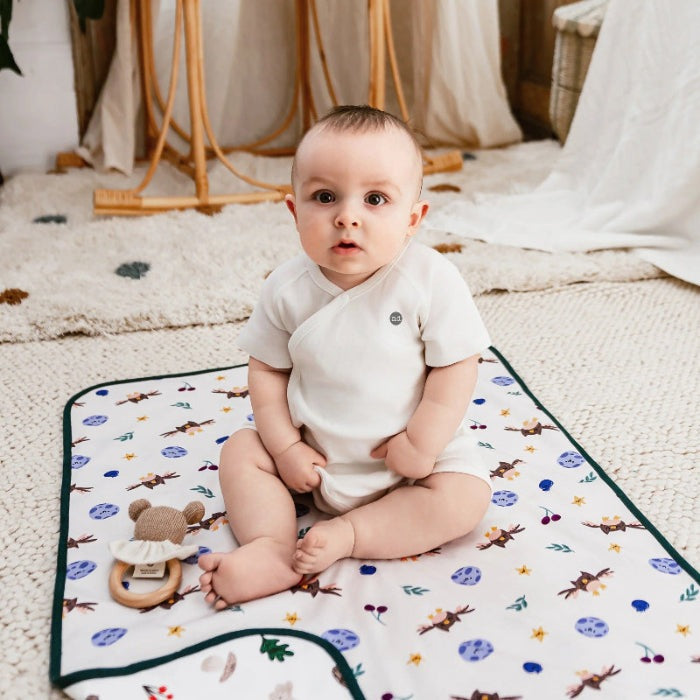 Nest Designs cotton waterproof baby change pad, small Fall Magic print with woodland animals, baby on mat