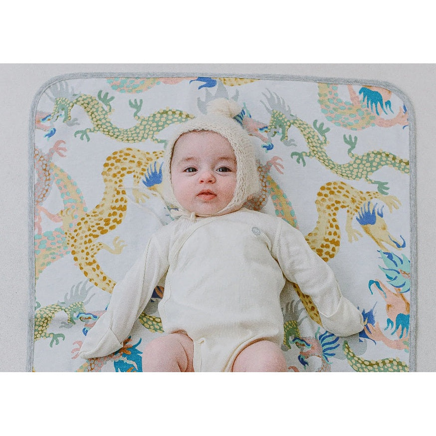 Nest Designs cotton waterproof change pad Dragon Dance print with a baby on it