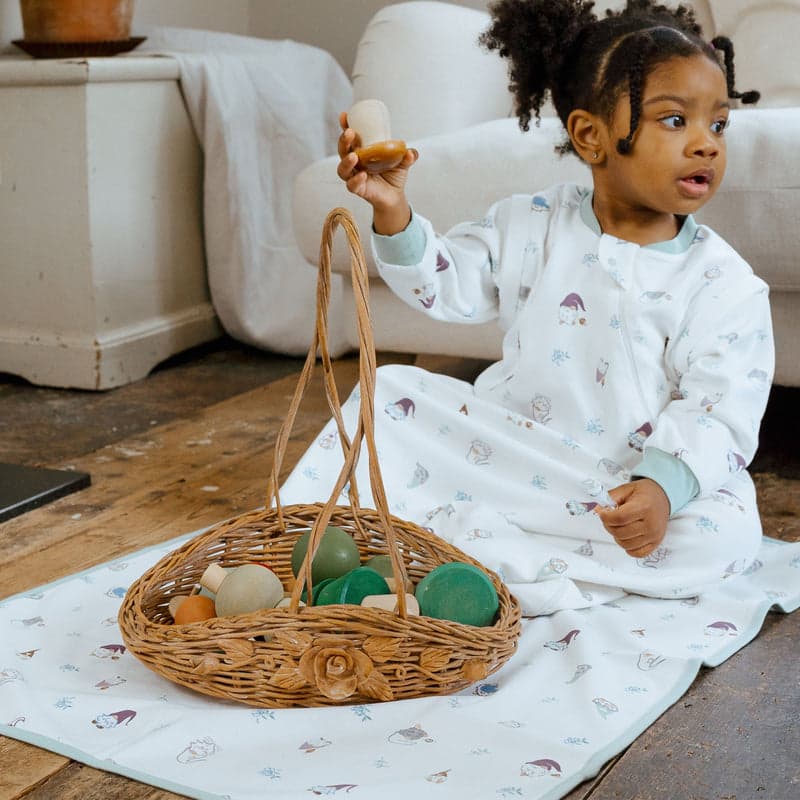 Nest Designs cotton waterproof change pad - Magic Mischief, toddler on a light blanket beside a wicker basket of colorful eggs