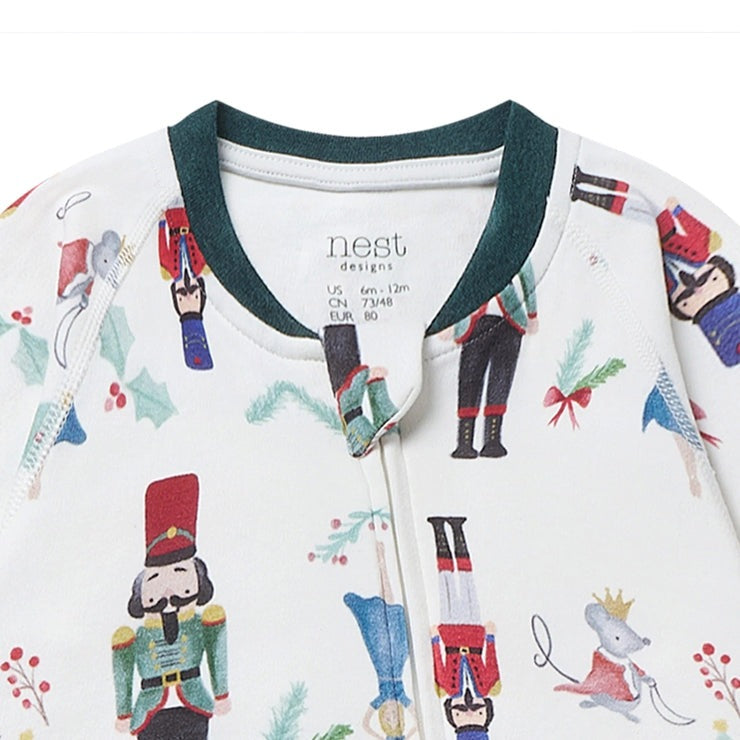 Nest Designs Organic Cotton long sleeve footed sleeper, white with Nutcracker print and green trim, zipper closure.