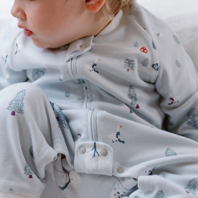 Nest Designs Organic Cotton Long Sleeve Footed Sleep Bag 1.0 Tog Snowy Snuggles, baby wearing it with visible snaps.