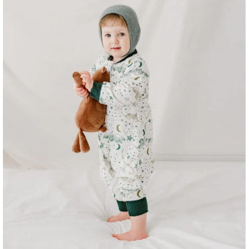 Nest Designs Organic Cotton Long Sleeve Footed Sleep Bag 1.0 TOG with stars; baby stands in white starry sack holding a plush toy