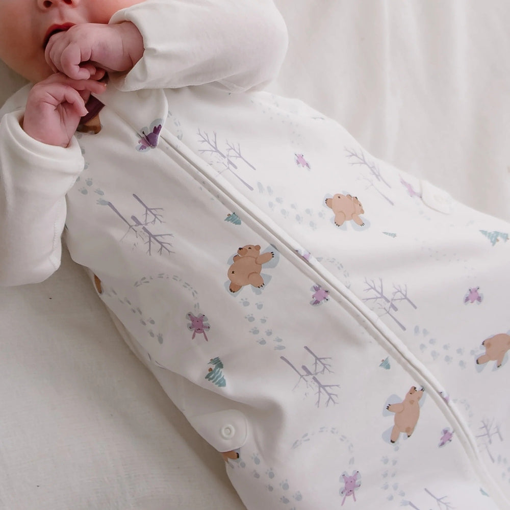 Nest Designs Organic Cotton Swaddle Sleep Bag 0.5 Tog Snow Angels; newborn baby zipped up in a white, bear‑pattern sleep sack.