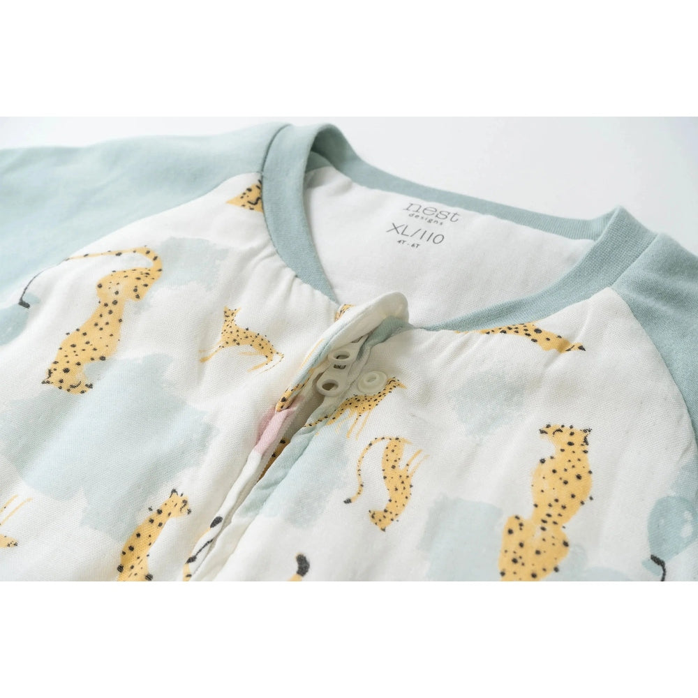 Nest Designs raglan bamboo long-sleeve footed sleep bag in cheetah party print with pale blue cuffs and chest snaps.