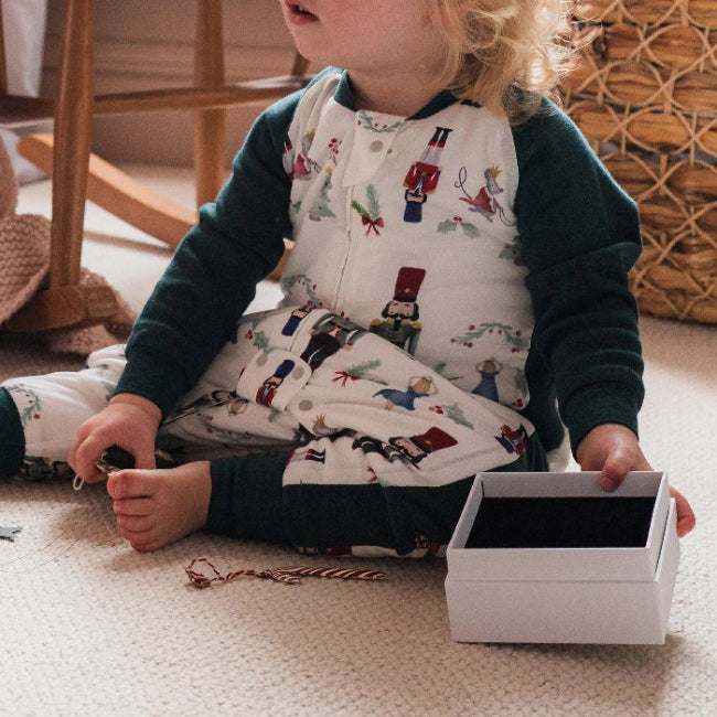 Nest Designs Raglan Bamboo Long Sleeve Footed Sleep Bag 2.5 Tog Nutcracker worn by a toddler on a cozy rug