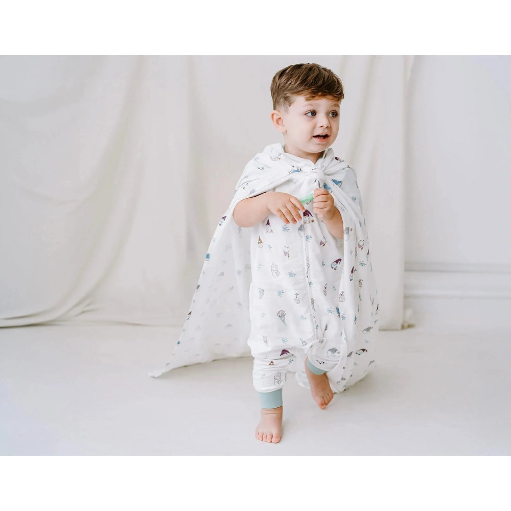 Nest Designs Raglan Bamboo Pima Sleep Bag Oh Gnome; toddler walks in a white footed sleep bag with blue cuffs.
