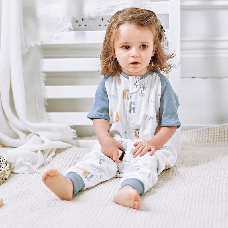 Nest Designs Raglan Bamboo Pima sleep bag in pastel waves, footed and 0.6 tog, as toddler sits on the rug.